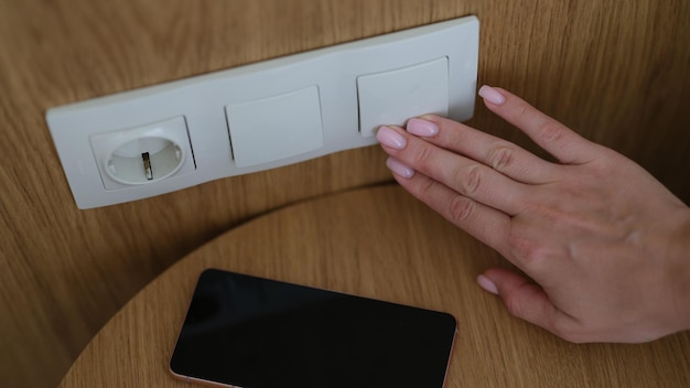 Woman hand presses on turn off lights close