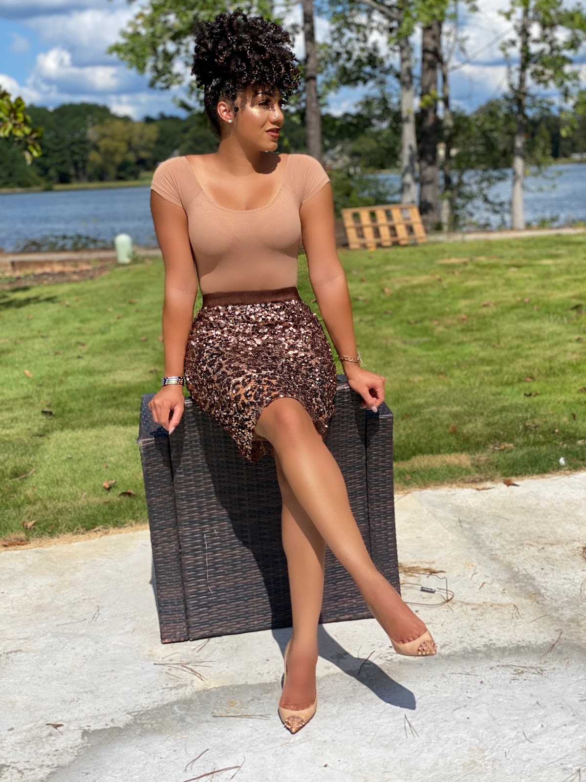 dr eva sitting on a chair in a grassy park with a tan shirt and sequins skirt