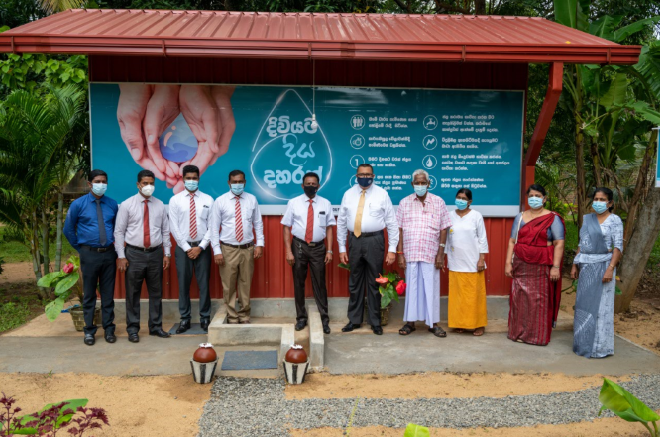 A group of people standing in front of a sign

Description automatically generated