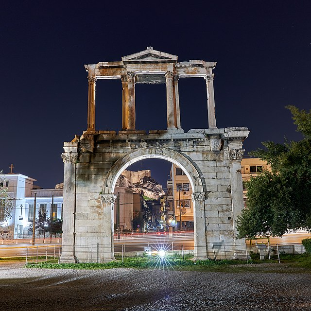 The Arch of Hadrian in Athens  at night, with the Acropolis seen in the distance.