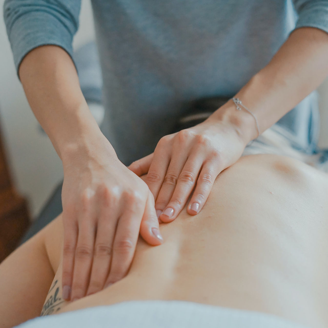 A person doing deep pressure therapy on the back of a woman.