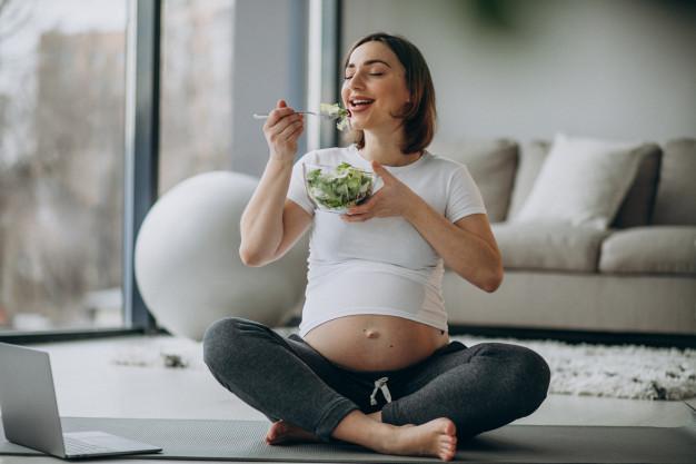Young pregnant woman eating salad at home Free Photo