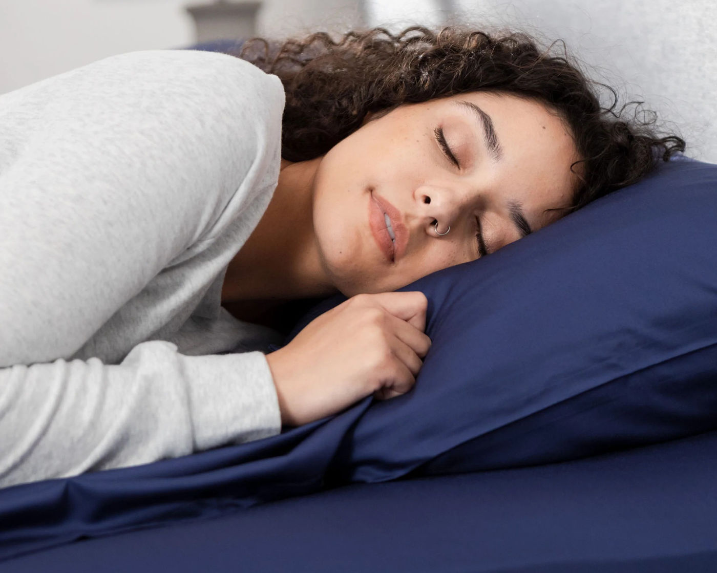 A young woman sleeping soundly on a blue Hush Iced Bamboo Cooling Sheet and Pillowcase Set.