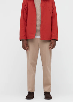 Photo of a Black model, from the shoulders down, wearing a red jacket and khaki stretchy pants.