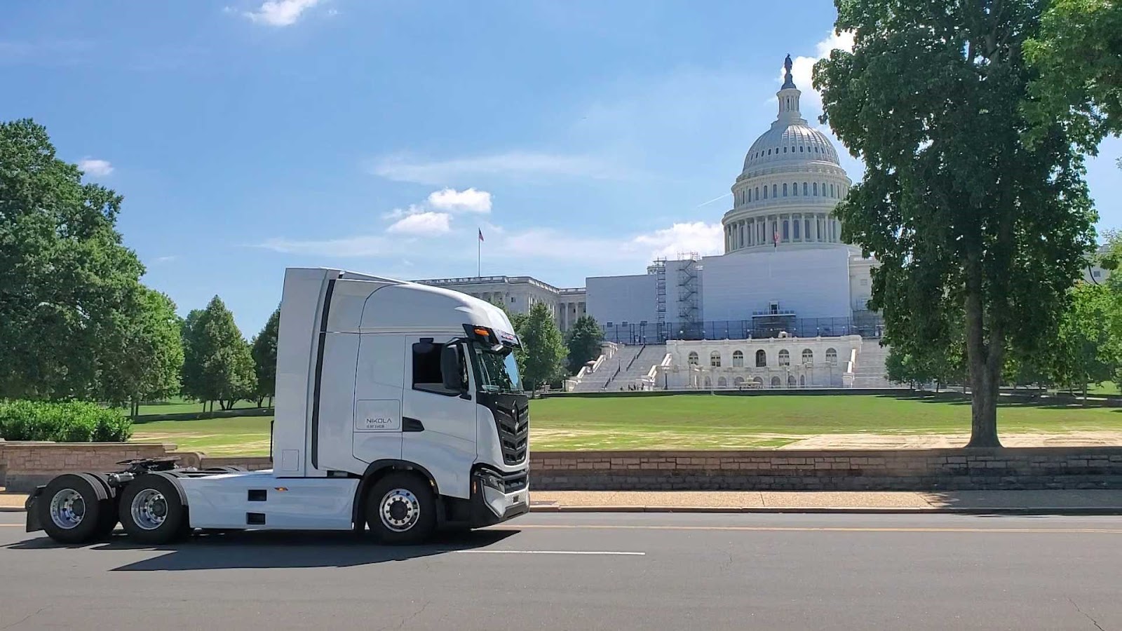 A white Nikola Tre Class 8 electric truck drives by the U.S. Capitol.