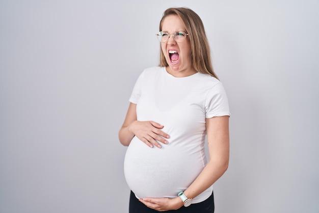 Free Photo | Young pregnant woman expecting a baby, touching pregnant belly  angry and mad screaming frustrated and furious, shouting with anger. rage  and aggressive concept.