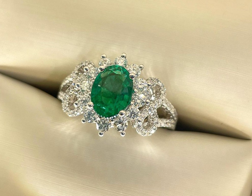 An intricate oval cut emerald and diamond ring in a ring box