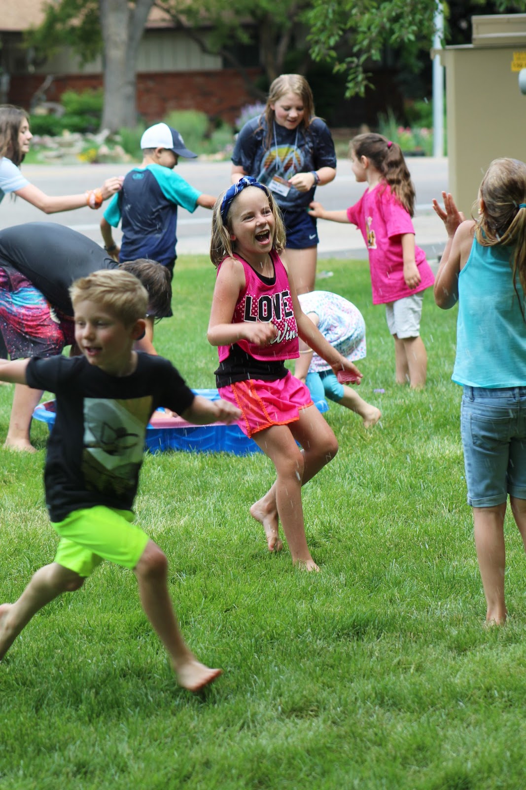 [Alt text: Children playing water games outside at Our Saviour’s Lutheran Vacation Bible School]
