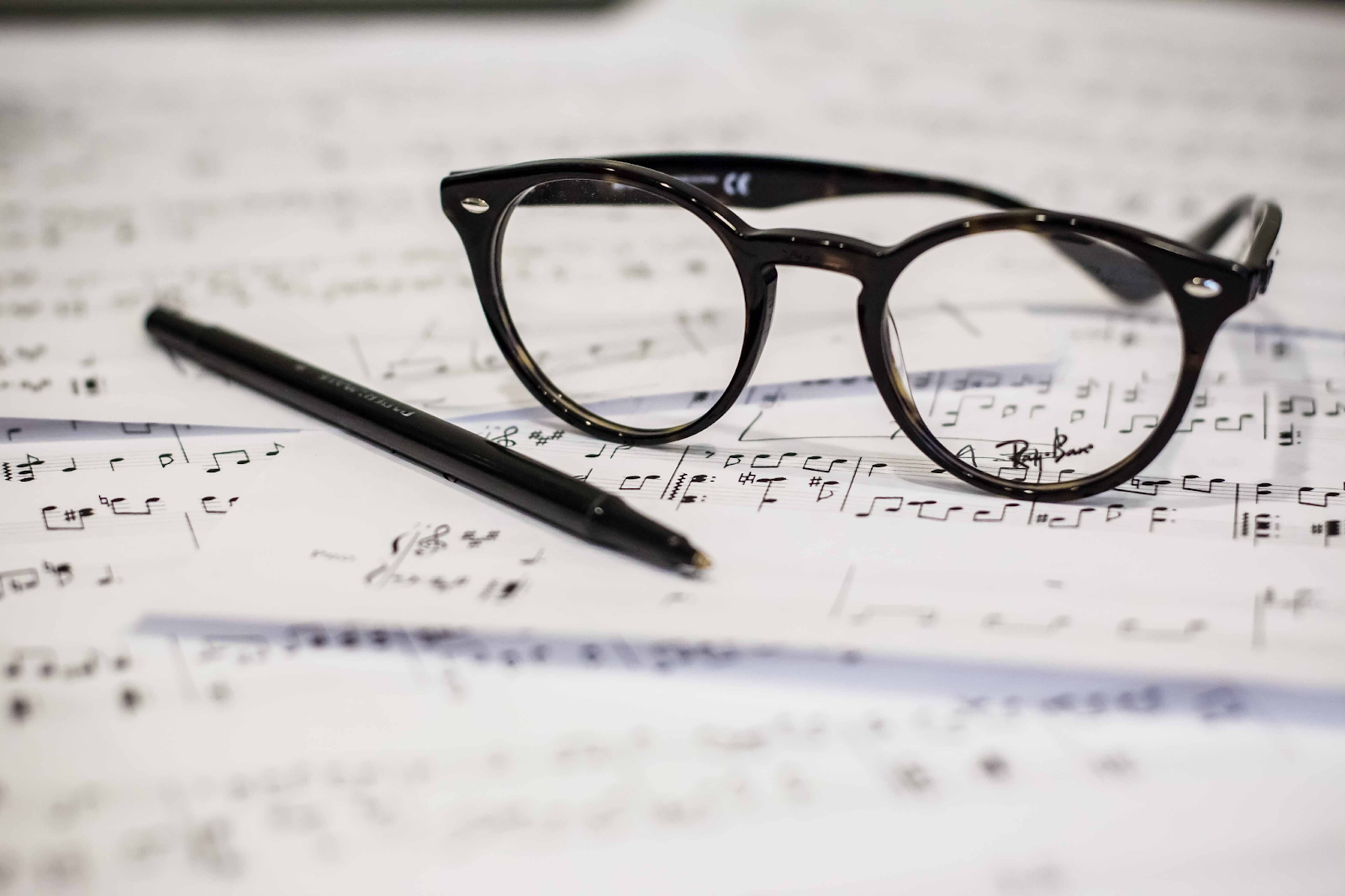 an eyeglass and ballpen on top of a music sheet