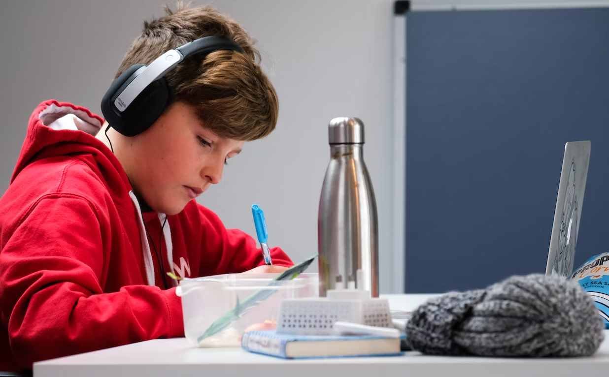 Boy working on school work with laptop and headphones