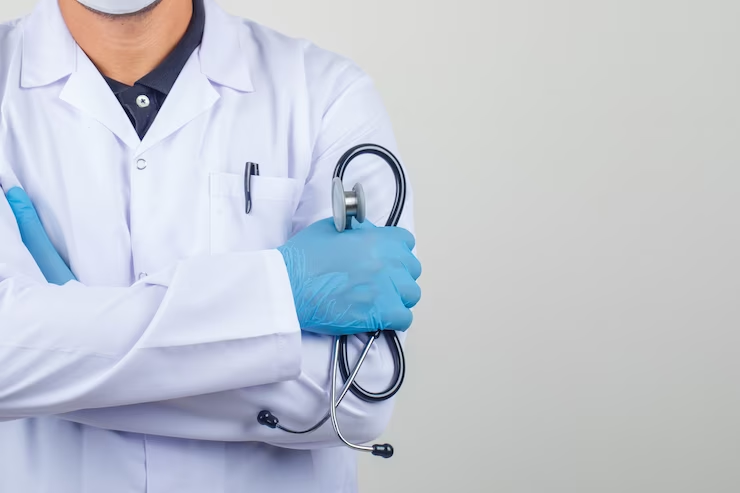 Public vs private medical school: a confident doctor in a white coat stands with arms crossed, holding a stethoscope. They project professionalism and expertise in their field.