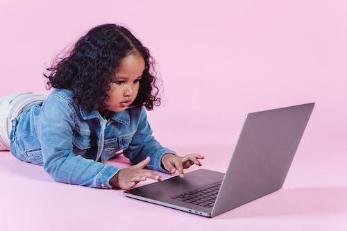 Free Adorable black girl browsing laptop on floor Stock Photo