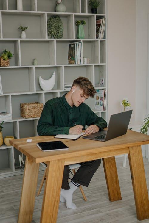 Man in Black Long Sleeve Shirt Sitting on Chair Using Macbook