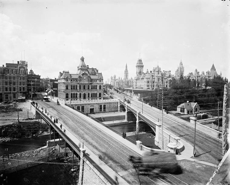 Old Ottawa Post Office. Sappers Bridge (left), Dufferin Bridge(right) over the Rideau Canal, 1890s. Today the War Memorial stands where the post office stood, with a new post office (now also old) on Sparks Street. The two bridges were replaced by the Plaza Bridge (Ottawa), and filled in. The centre block of the parliament buildings was replaced after a 1916 fire.
