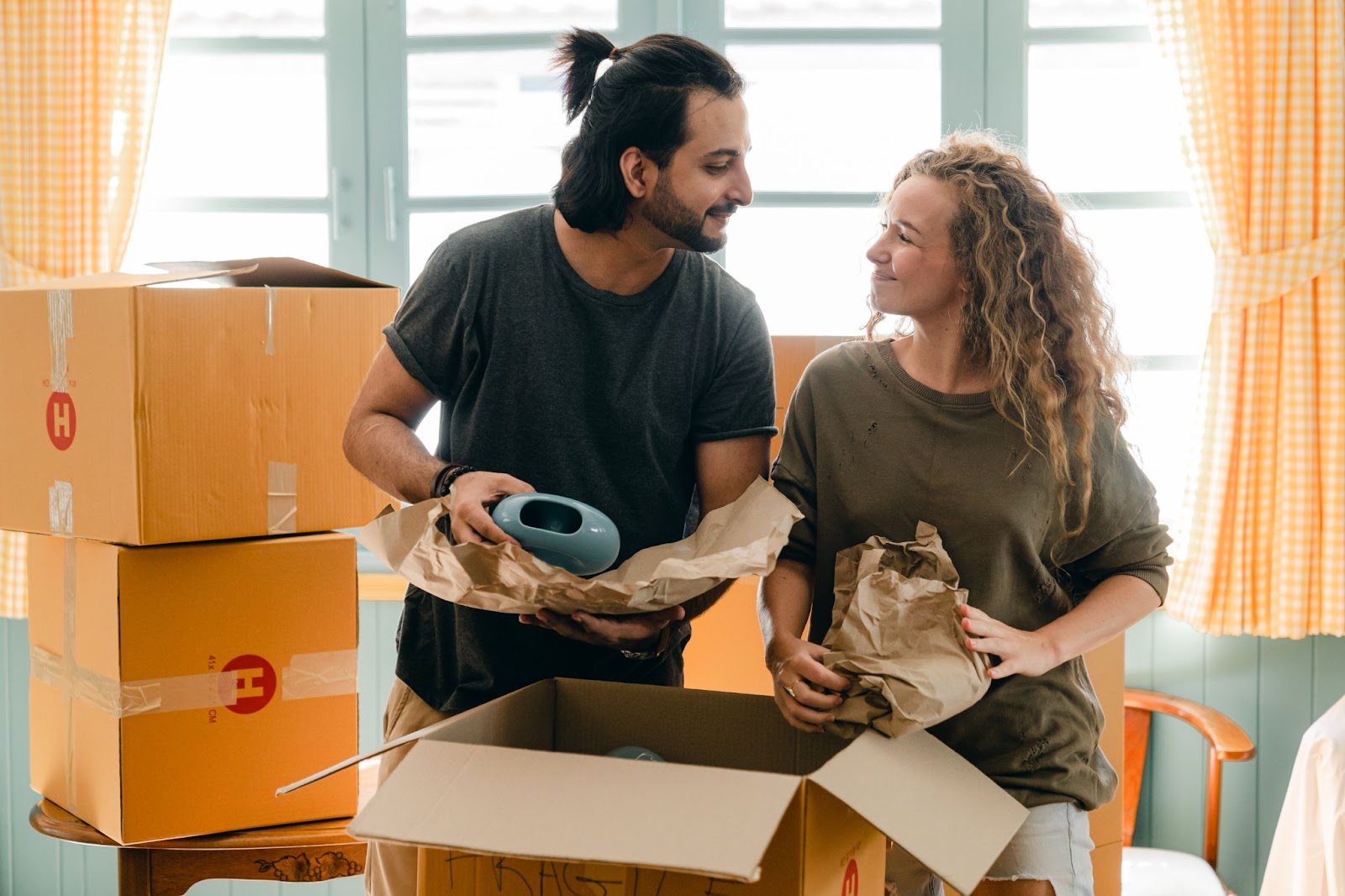 couple smiling at each other while unpacking boxes