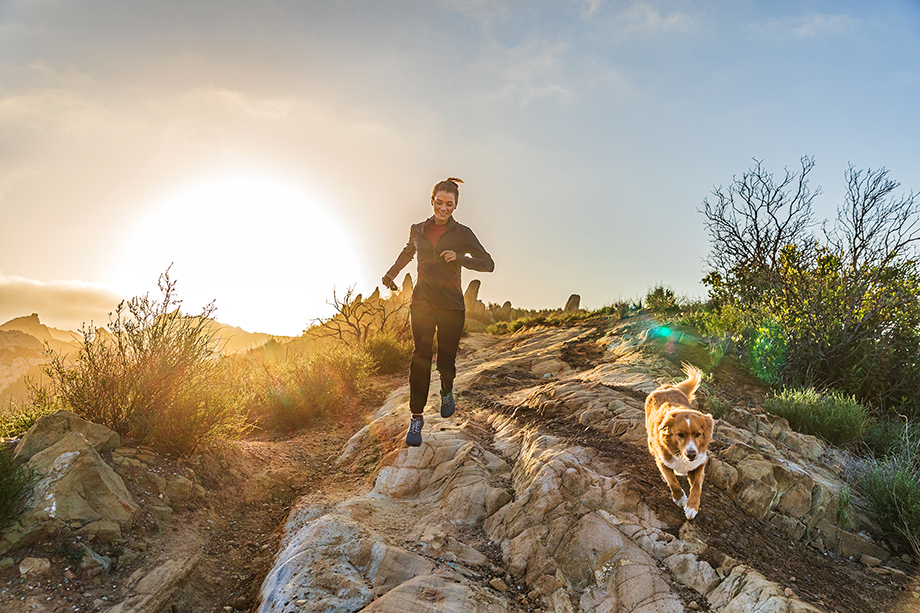 Woman and dog run over rocky terrain in the Santa Monica Mountains shot by Lou Bopp for the Purina Pro Plan campaign.