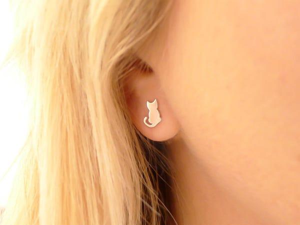 closeup photo of a sterling silver cat earring worn by a blonde-haired person