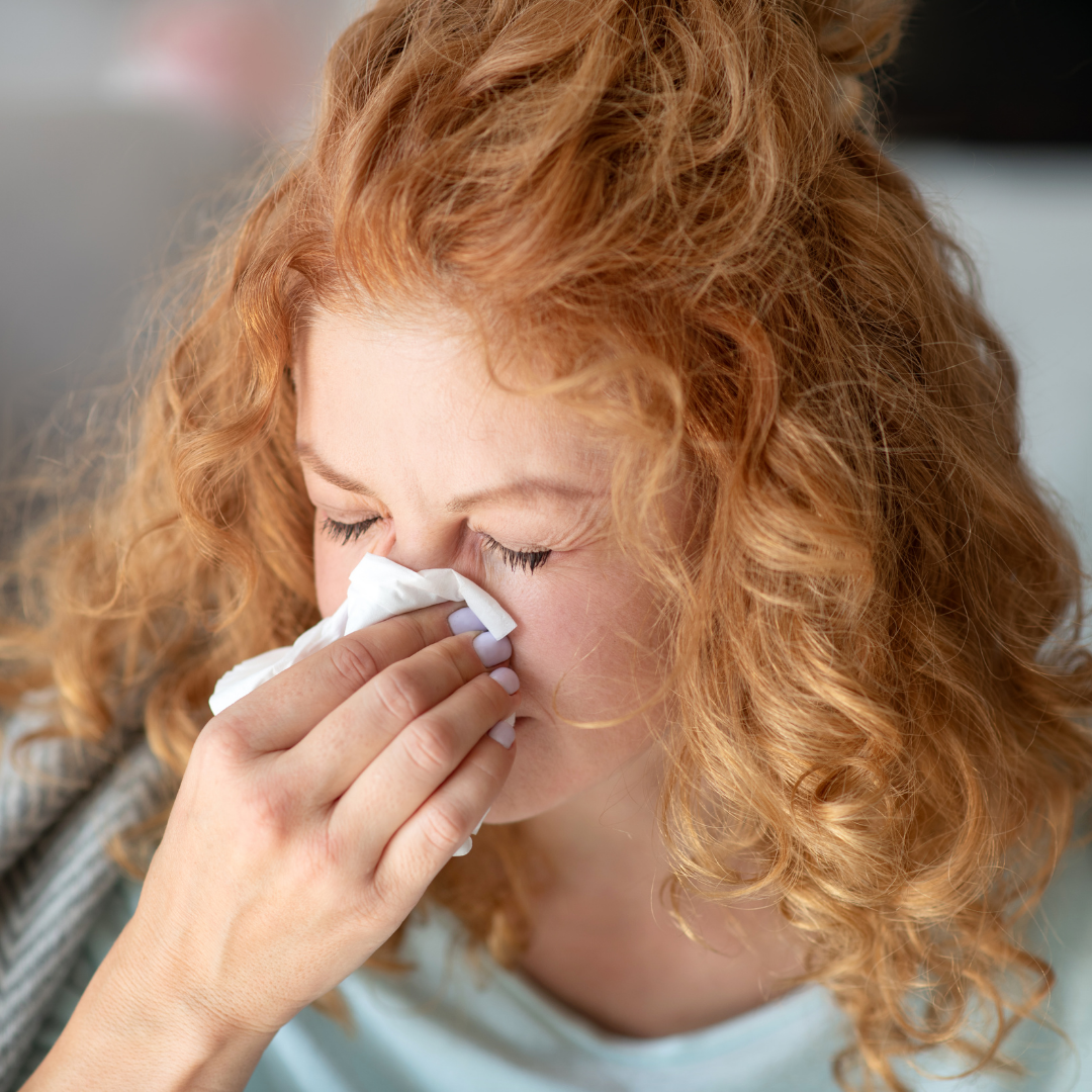 Woman blowing her stuffy nose with a tissue 
