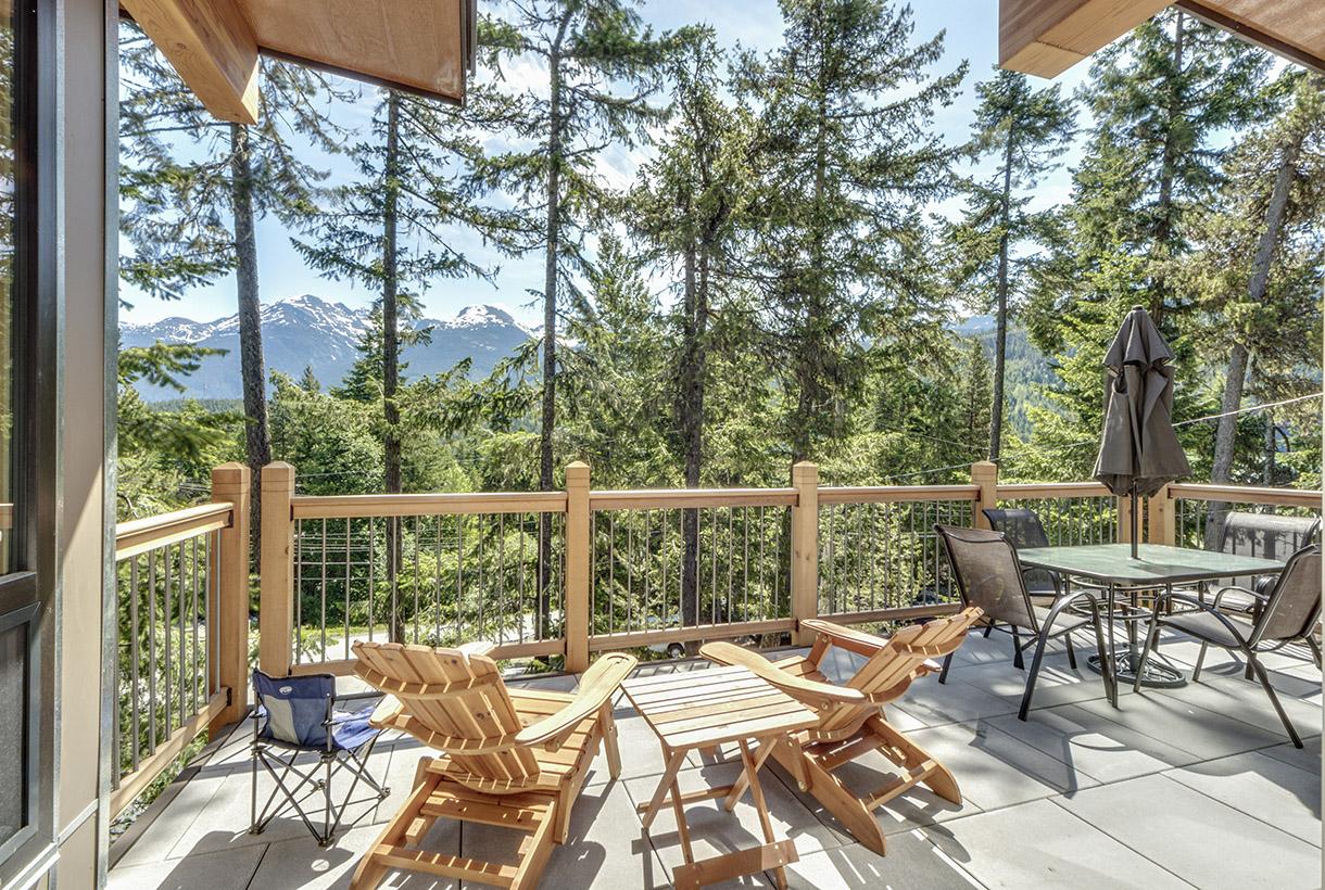 WeServe home deck with wooden and metal chairs and tables with trees and mountain view