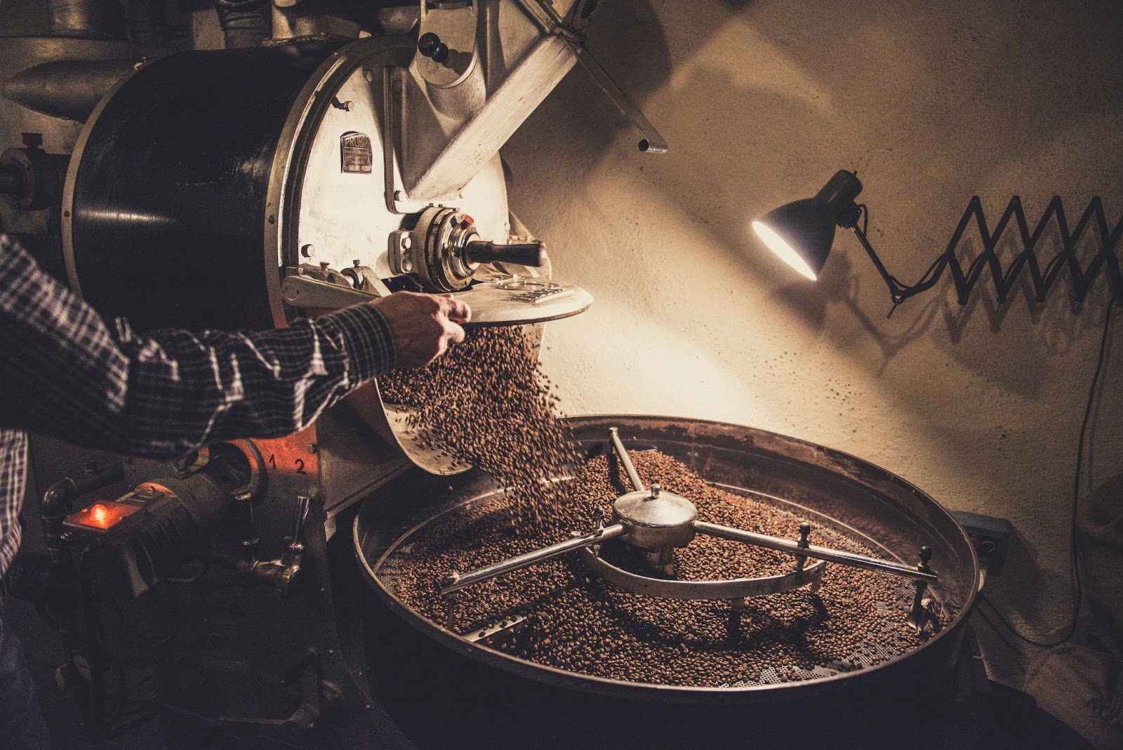 Coffee beans pouring into a roasting machine.