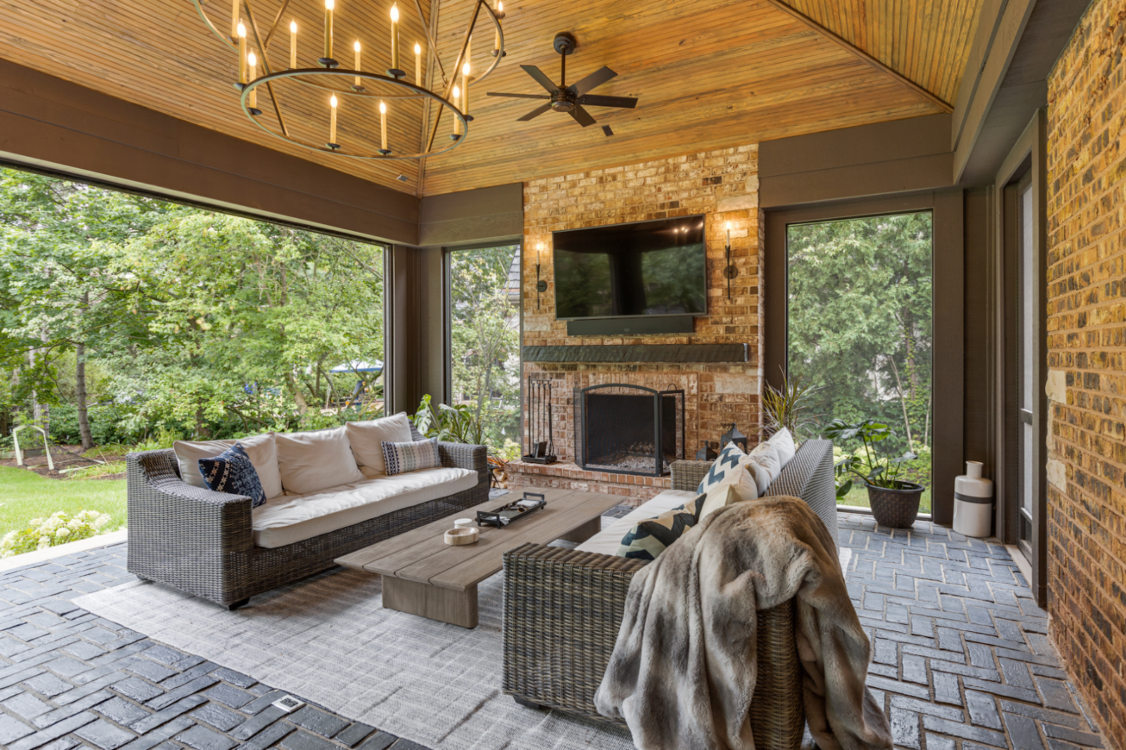An outdoor covered porch with brick fireplace and dual couch seating makes a great conversational spot