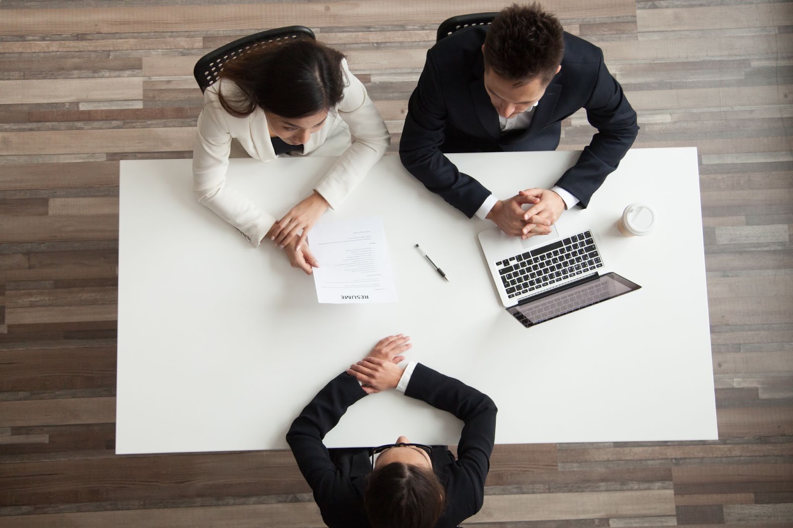 a group of people sitting at a table with a laptop and papers 