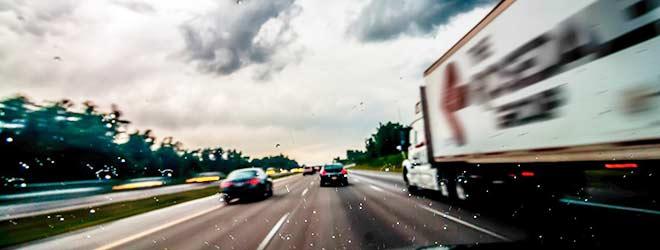 Two vehicles and a semi driving down a highway.