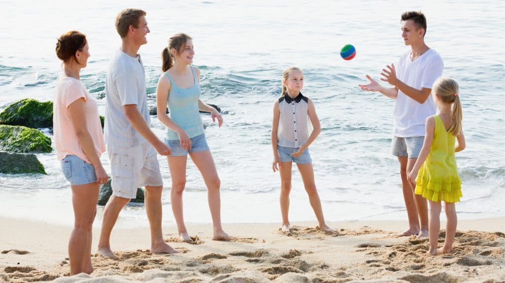 Famille-nombreuse-tableau-d-organisation-jeux-en-famille : des parents jouent au ballon sur la plage avec leurs quatre enfants