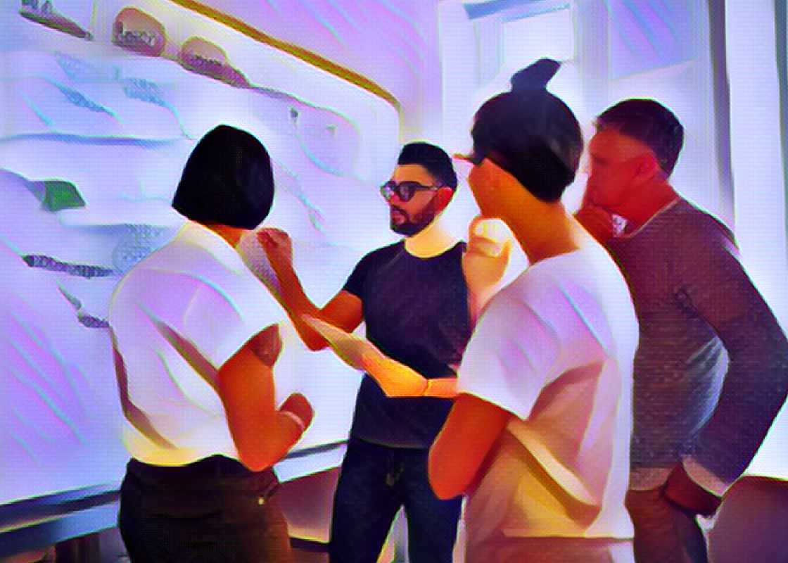 4 young digital marketing executives stand around a whiteboard brainstorming techniques to drive growth. 