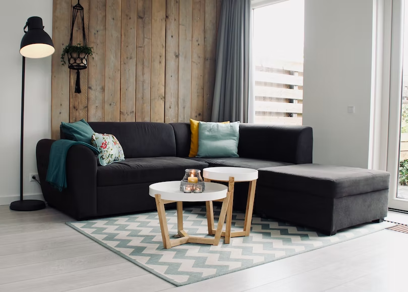 A living room with a black sofa and two small round white tables