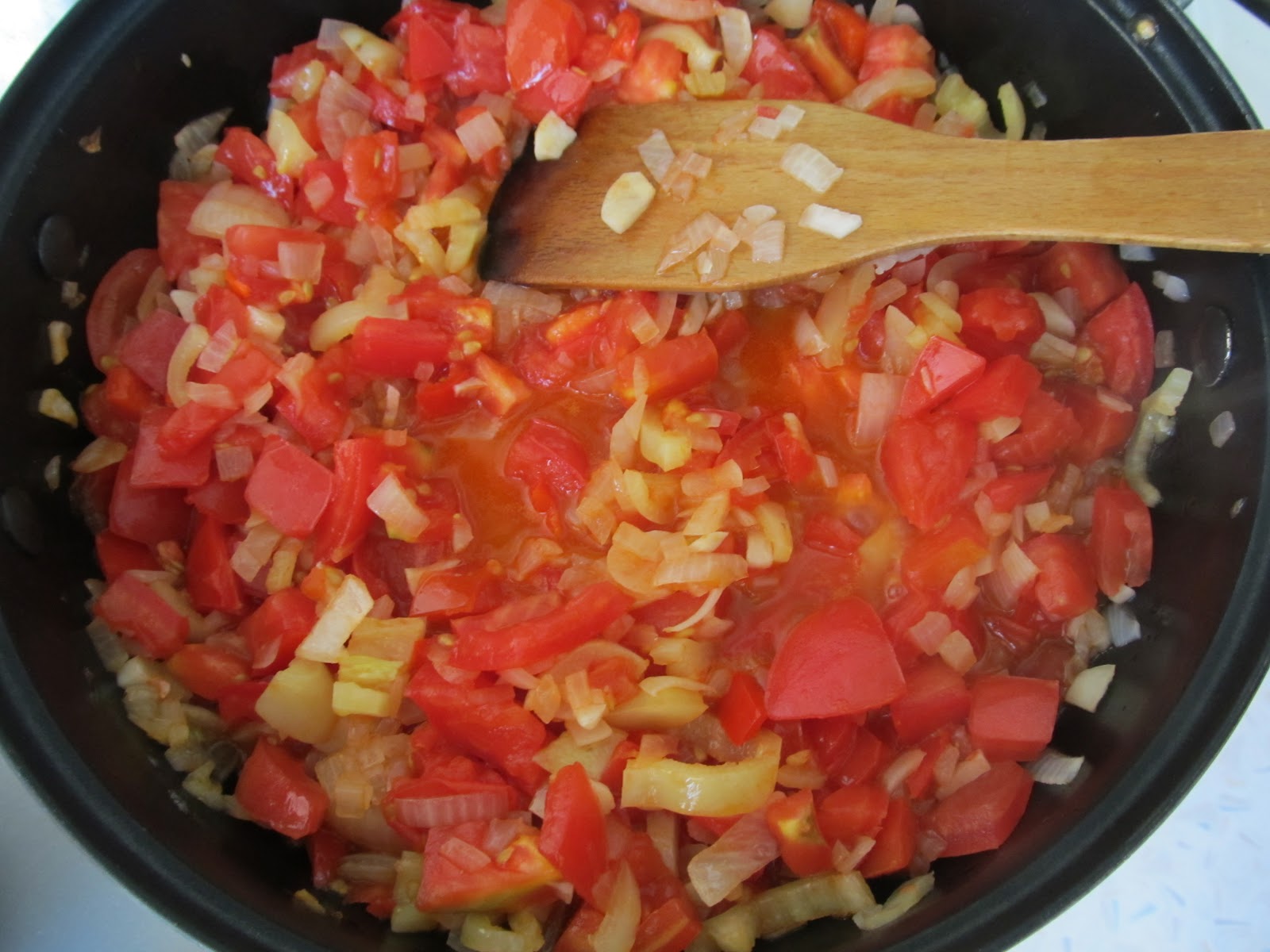 додавання помідорів до обсмаженої цибулі, часнику та перцю