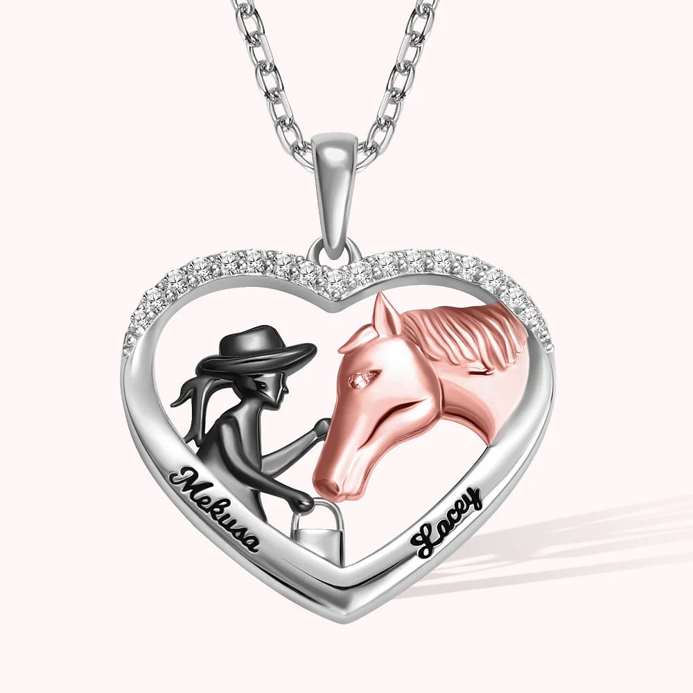 Collier argenté en forme de coeur présentant à l’intérieur une cavalière en noir et un cheval en rose, dont l’oeil porte une pierre argentée.