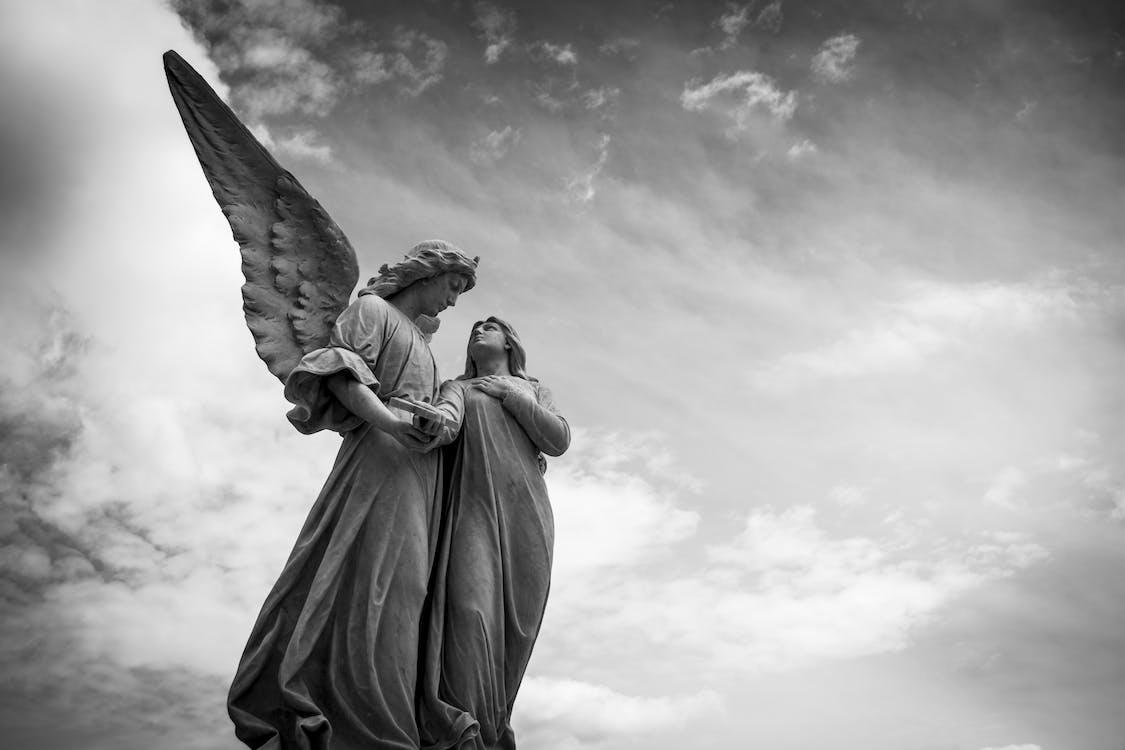 Free Grayscale Photography of Angel Statue Under Cloudy Skies Stock Photo