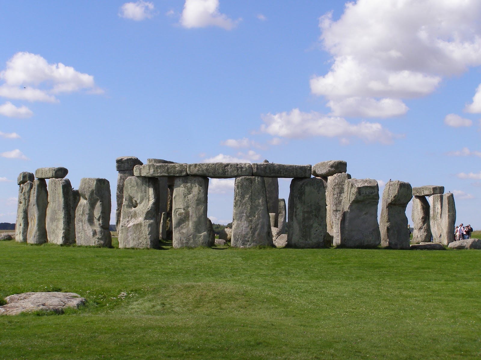 stonehenge natural wonder of the world. Rock formation on a green lawn during a sunny day, some tourists near the right end of the frame.