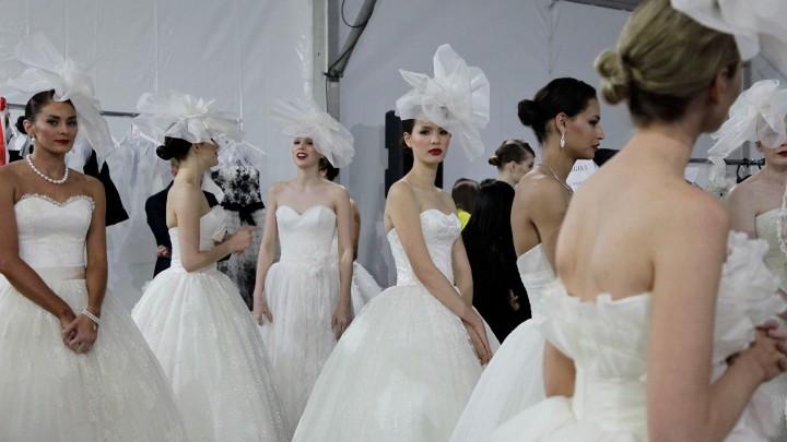 A group of women in white bridal dresses and headpieces. 