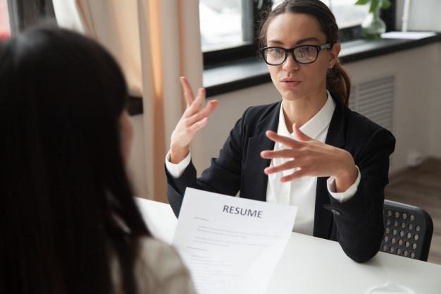 Confident millennial female applicant in glasses talking at job interview