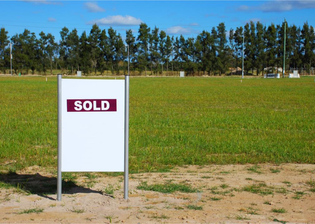 Sold sign in front of a plot of land.