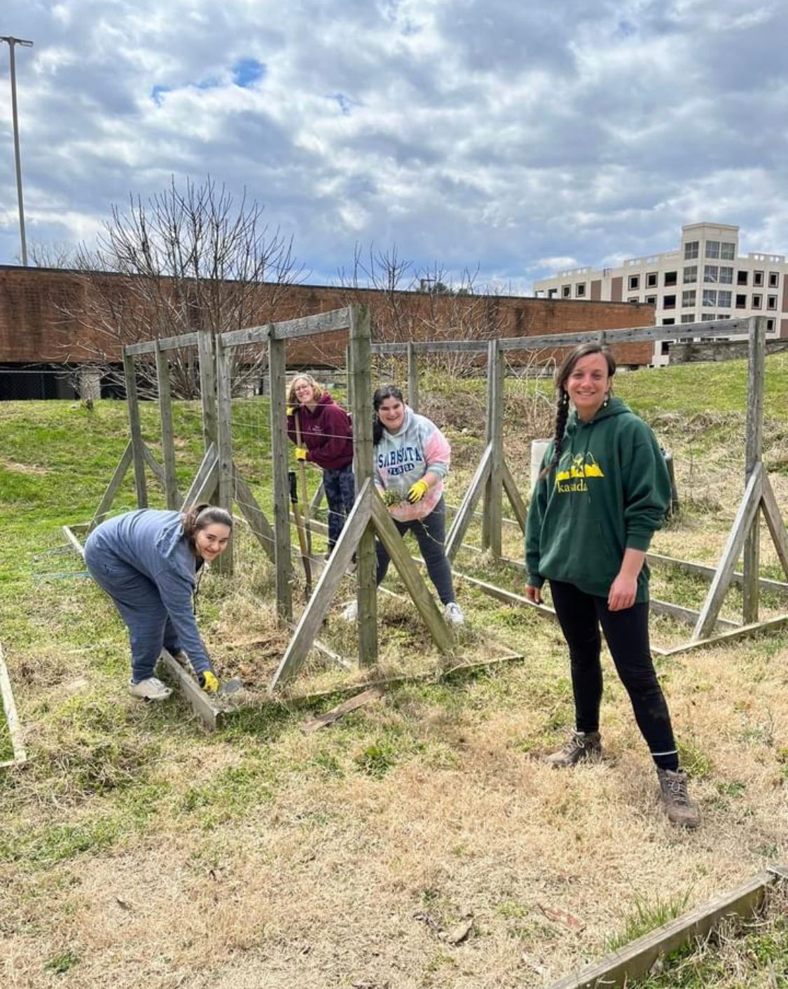 Students pose in a garden by wooden trellises