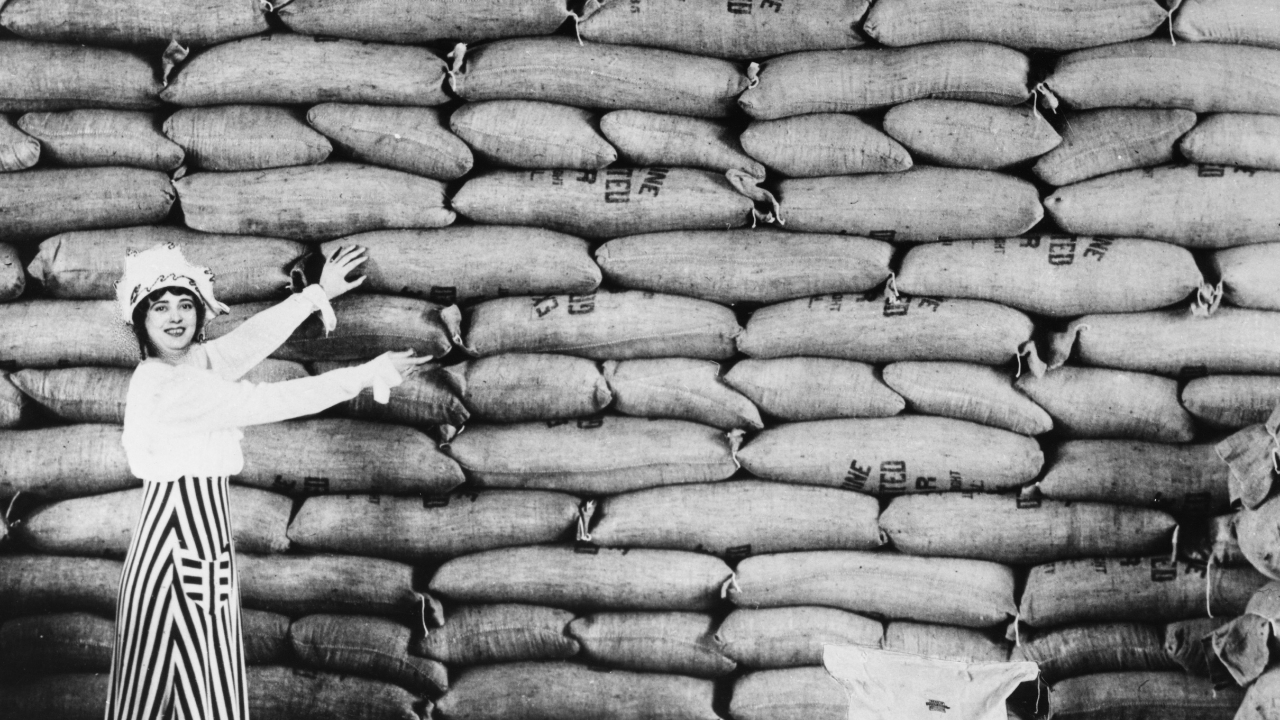 A woman gesturing to a wall of feed bags