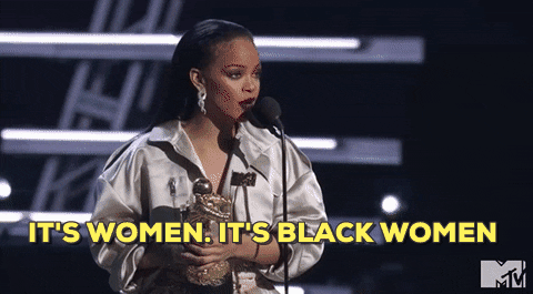 Rihanna on stage at an award ceremony (flashes to the audience) holding an award and saying into a microphone "It's women. It's Black women."