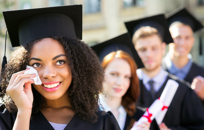 Female graduate standing in line wiping face with a tissue