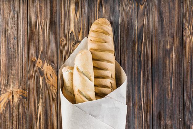 Baguettes wrapped in the paper over the wooden background Free Photo