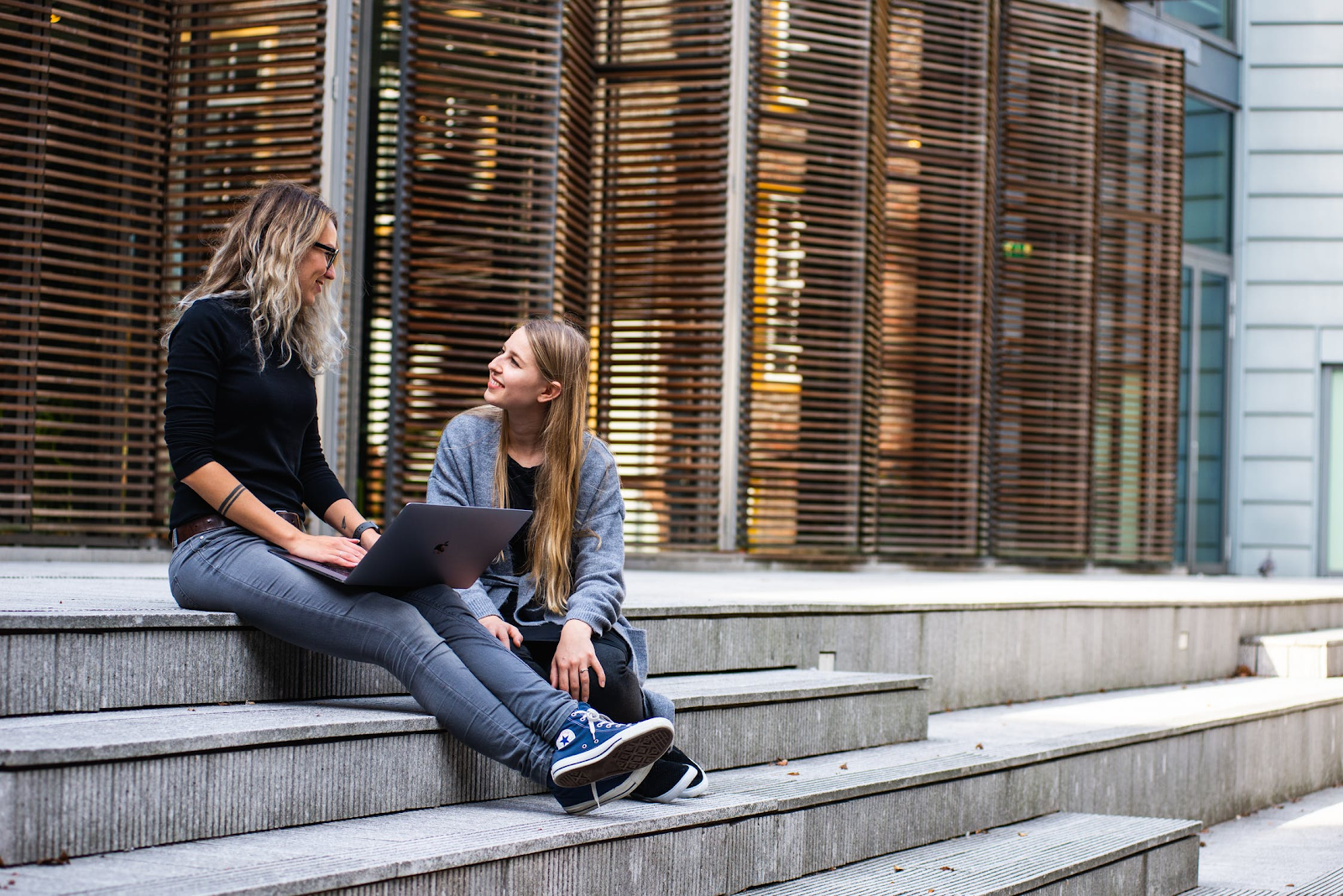 Two women sitting on stairs outside of a building