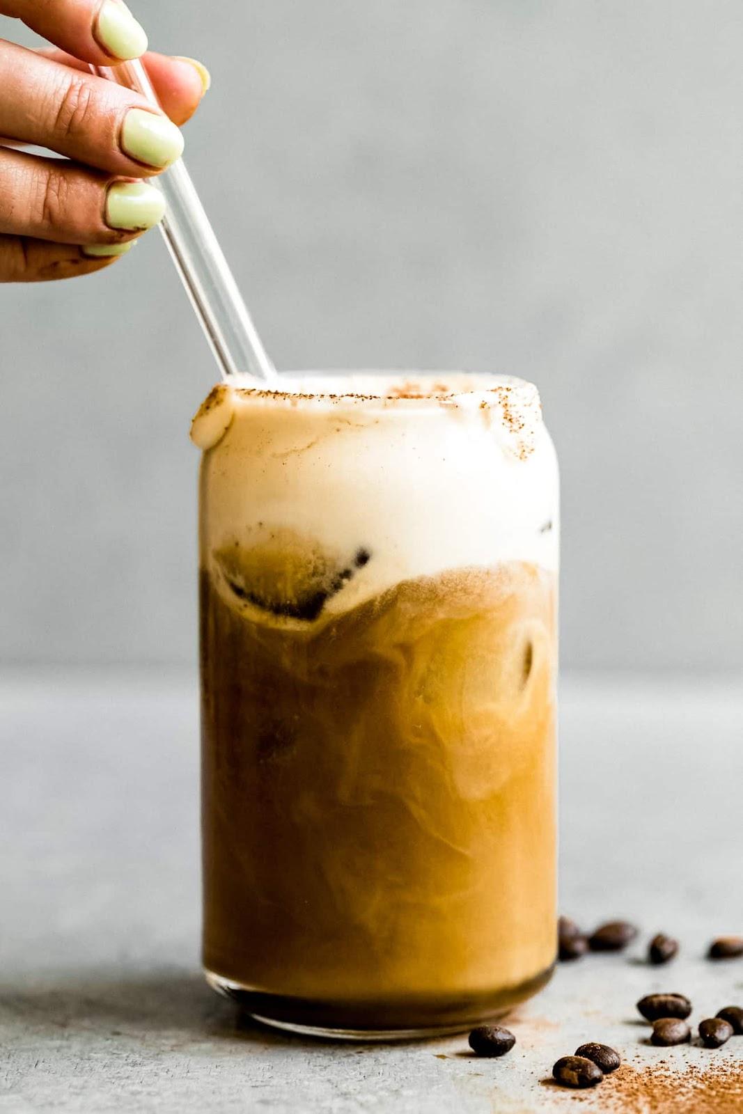 stirring irish cream coffee in a clear glass