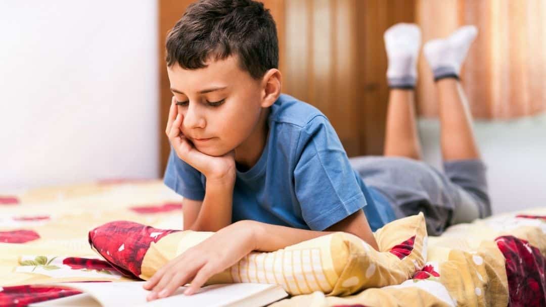litte boy reading on his bed - child writes letters backwards