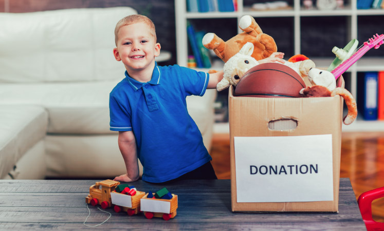 A little boy putting toys in a donation box