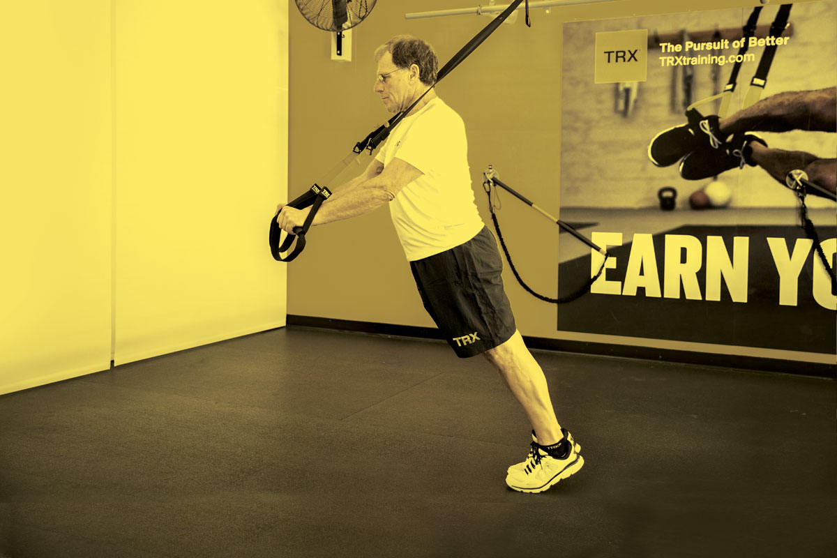 Man doing standing plank with TRX