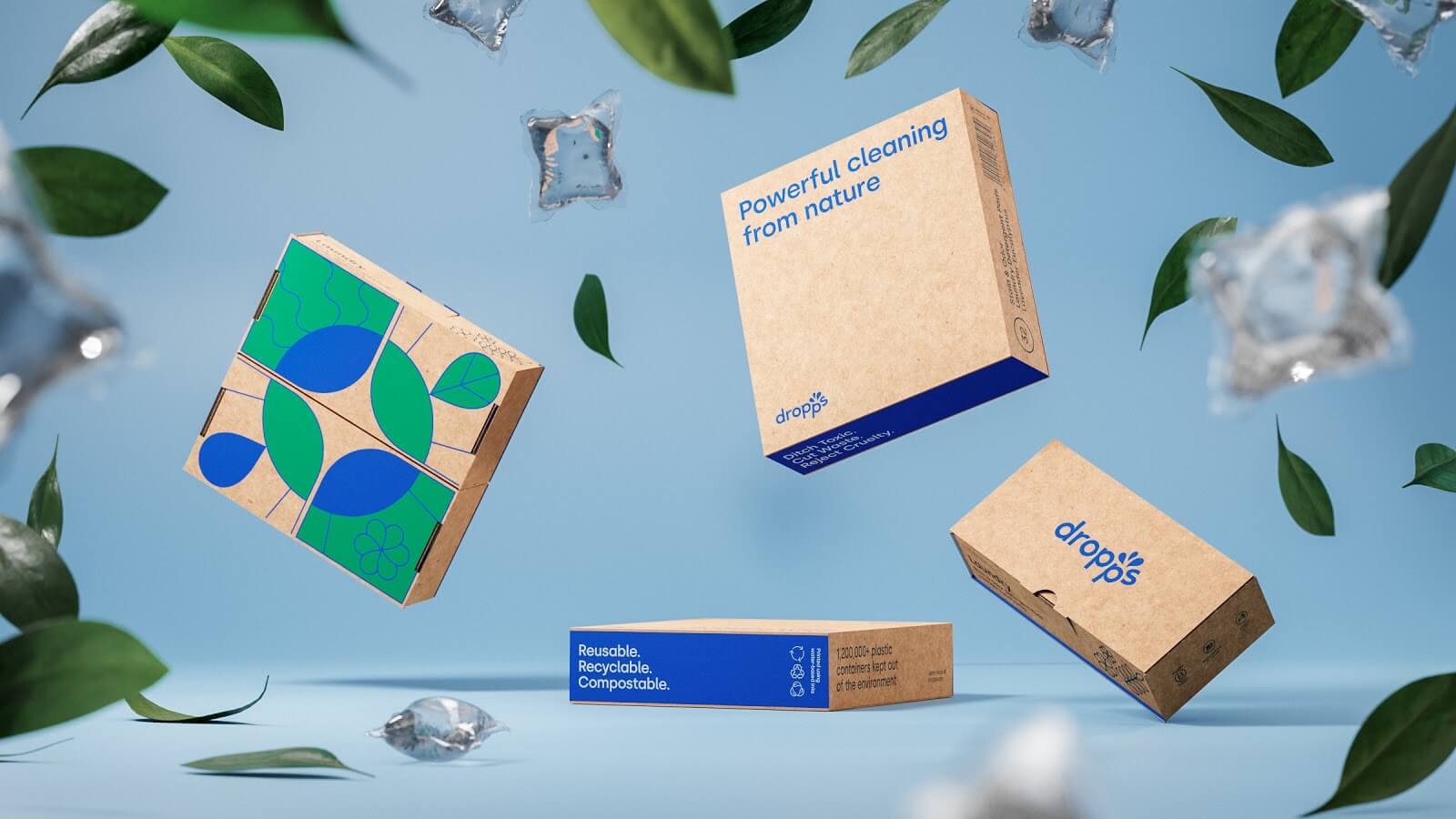 Feeling Fresh and Cleaning Up the Laundry Industry with Dropps–A baby blue background with four boxes of Dropps’ detergent pods in the foreground. They are surrounded by green leaves and clear laundry pods, staged as if everything was thrown in the air.