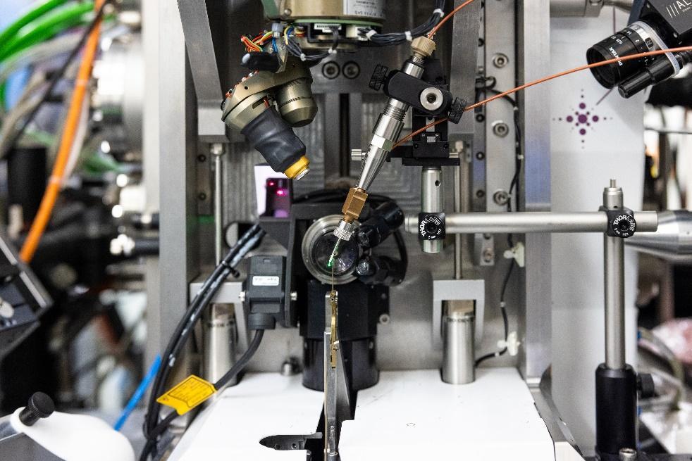 Photo of the time-resolved X-ray crystallography setup at EMBL Hamburg’s beamline P14. There is the sample injector in the centre, mounted with metal holder seen on the right side of the picture. The camera with microscopy objective is at the back.
