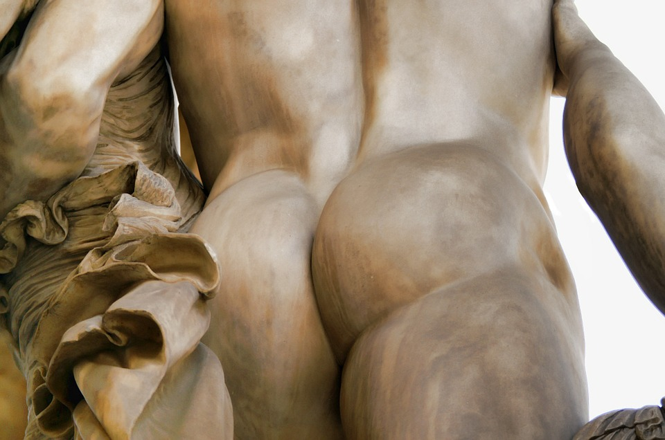 Close up of a bronze male statue’s posterior.
